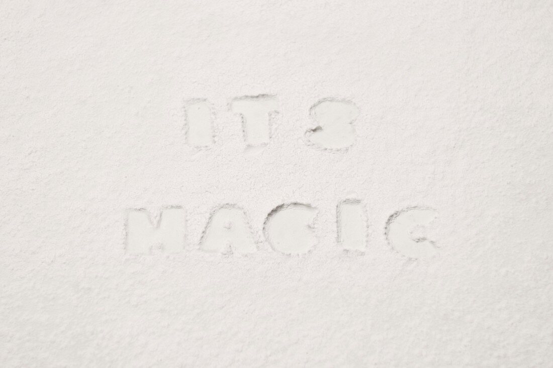 Lettering reading 'IT'S MAGIC' pressed into flour
