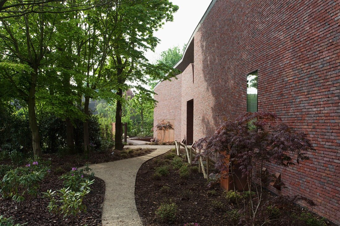 Meandering garden path along mainly solid brick facade of modern Belgian house