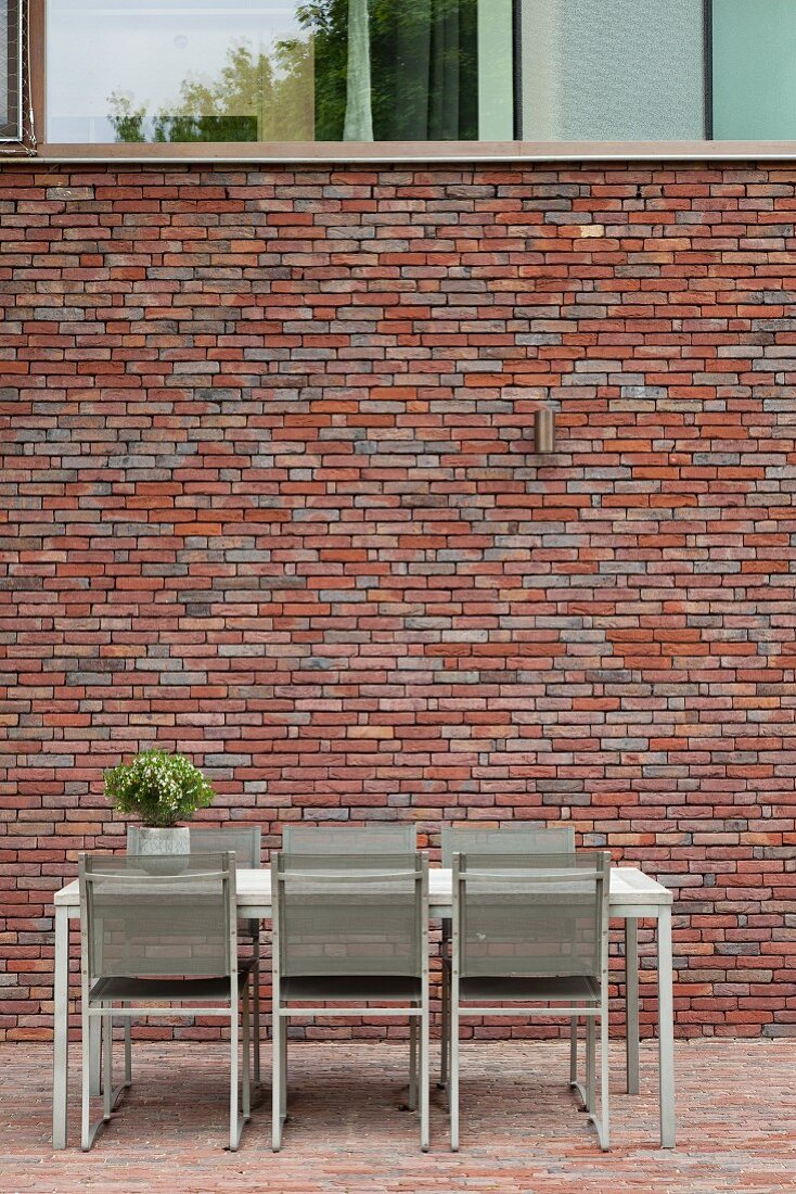 Simple, modern outdoor dining area against brick facade with glazed upper storey
