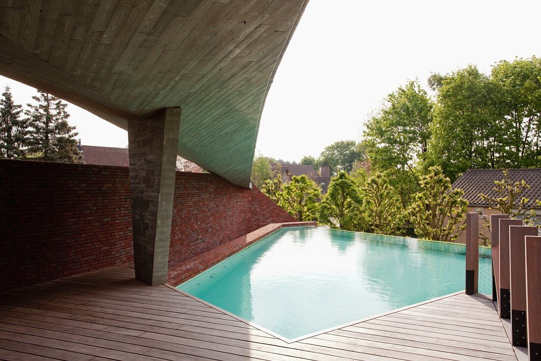 Expressive Formgebung eines Betondachs über der Sonnenterrasse an polygonal angelegtem Pool