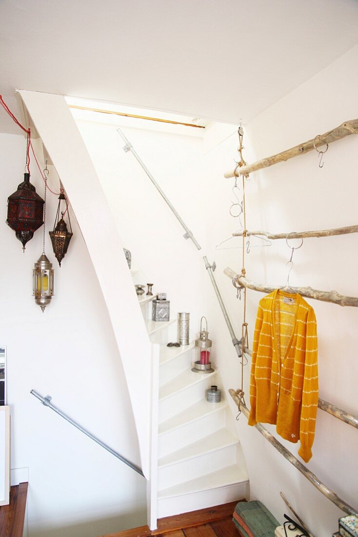 Schmale Treppe mit orientalischen Leuchten, seitlich ein DIY Hängegestell für Kleidung aus Ästen