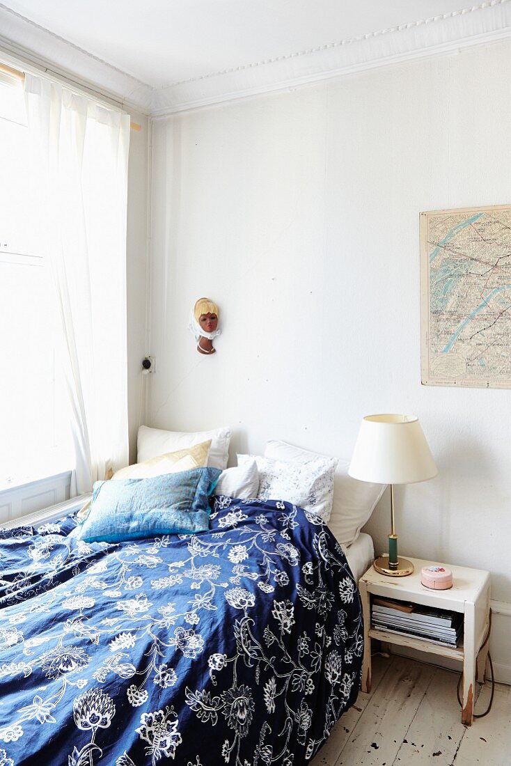 Bed with blue and white patterned bed line in corner of simple room