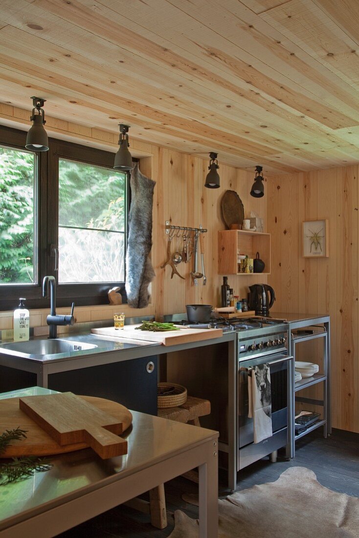 Minimalistische Küchenzeile vor Fenster in holzverkleideter Waldhausküche