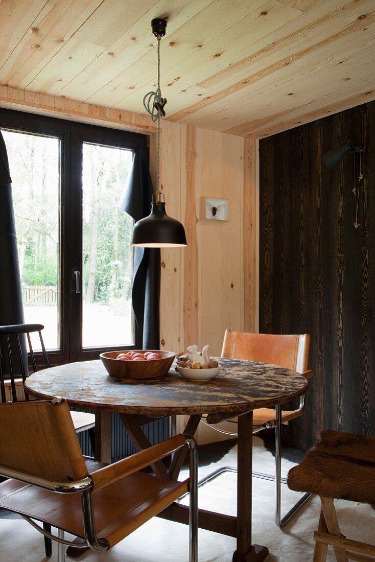 Freischwinger mit hellbraunem Lederbezug um rundem Holztisch in Hüttenambiente