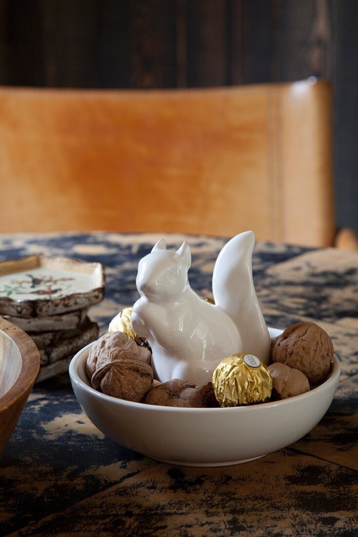White, chine squirrel in dish of walnuts and chocolates
