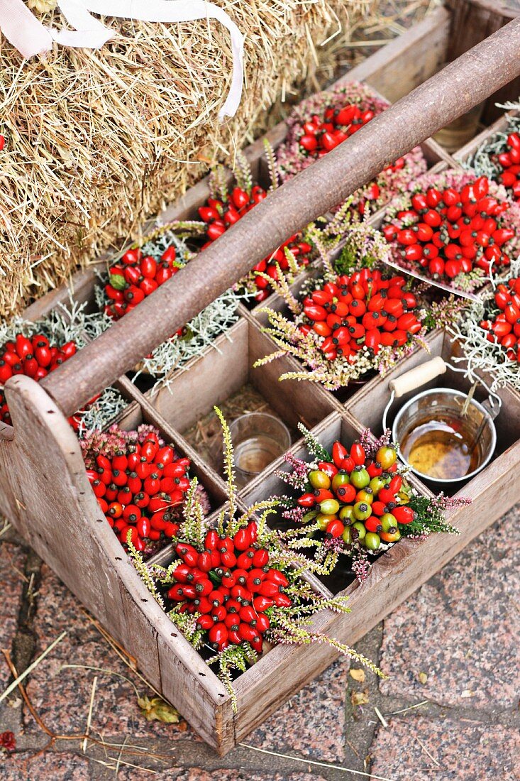 Posies of rosehips and heather in wooden crate