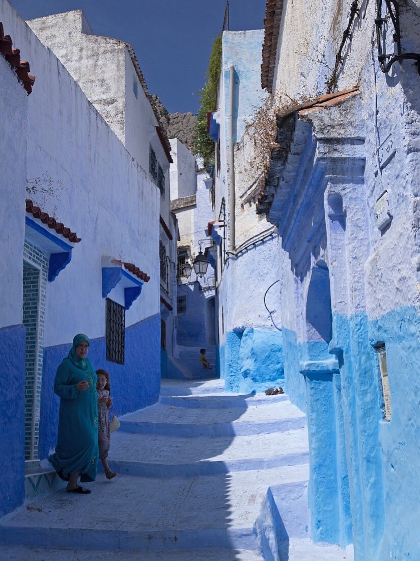 Frau und Mädchen in einer blauen Gasse in der Medina von Chefchaouen, Marokko