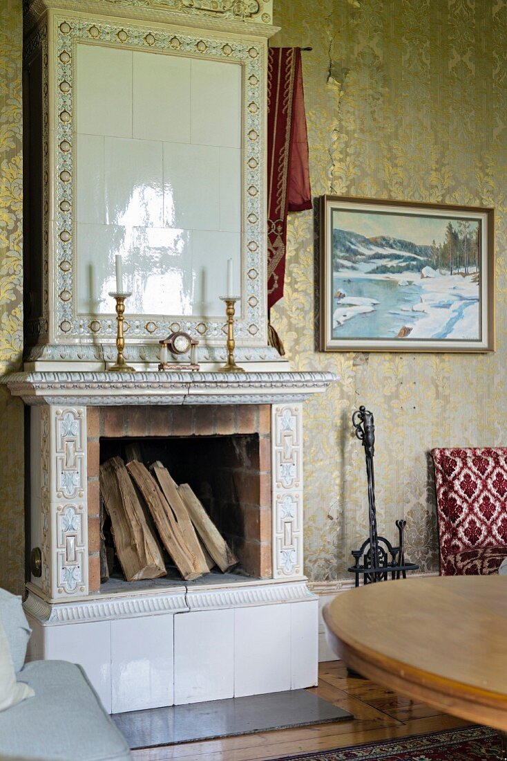 Weiß gefliester, offener Kamin, auf Kaminsims Kerzenhalter in traditionellem Wohnzimmer