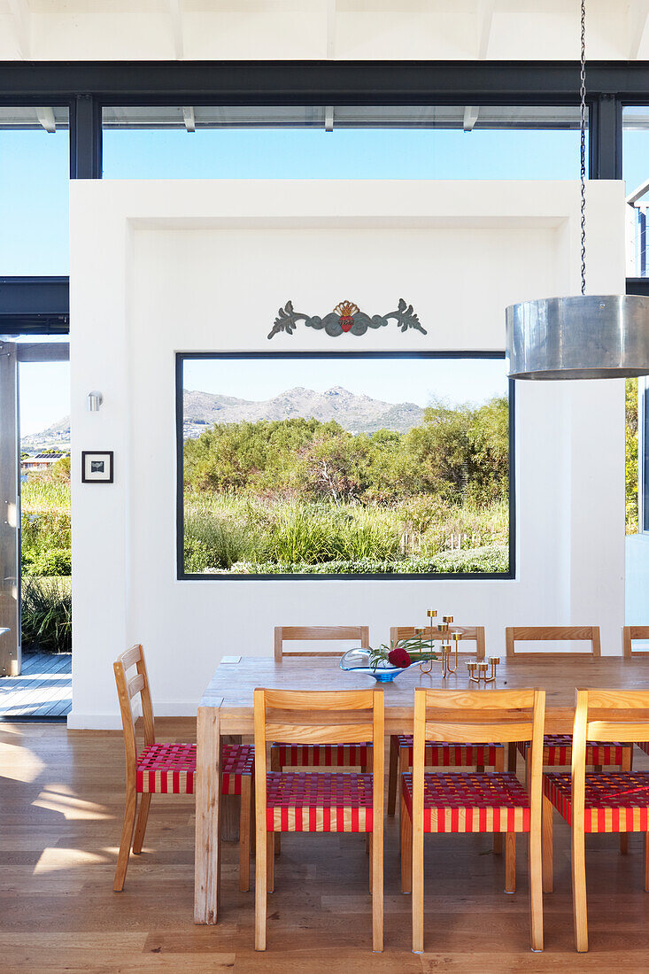 Dining area in front of white partition wall with panoramic window in modern interior