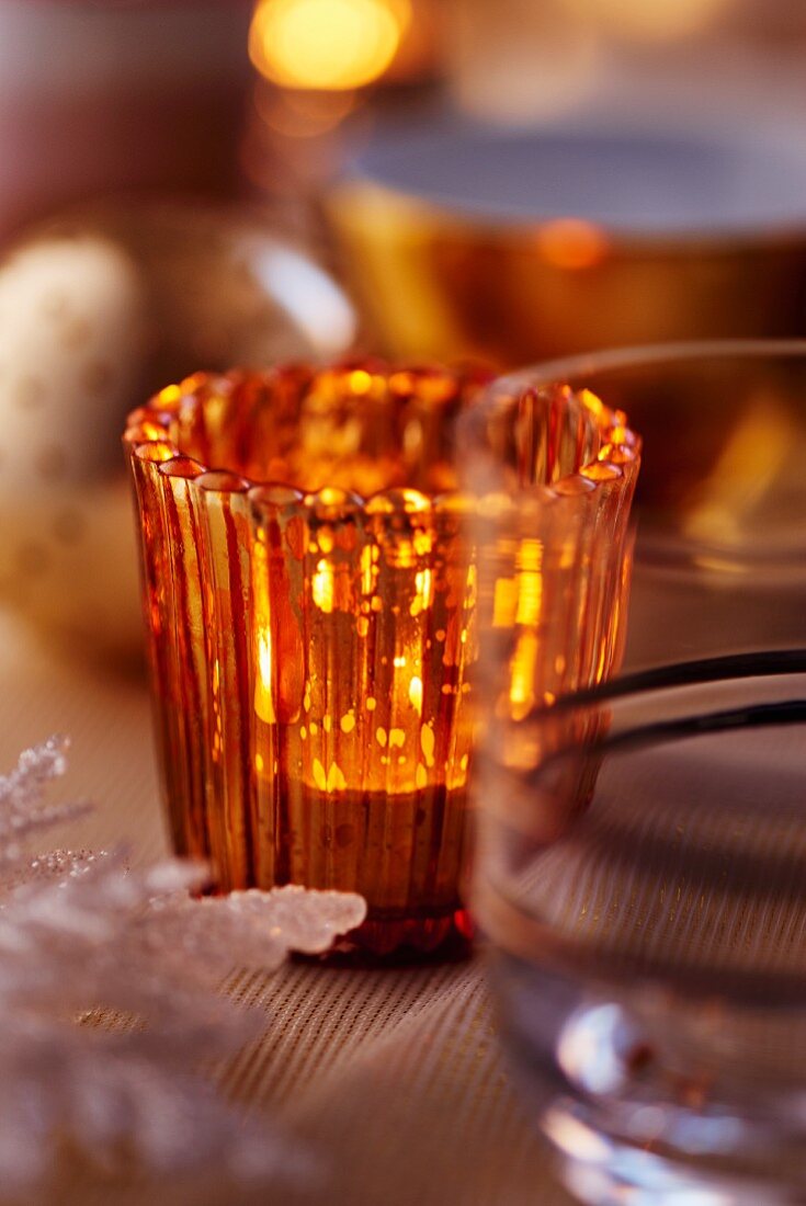 Orangefarbenes Teelicht als Tischdeko für Weihnachten (Close Up)