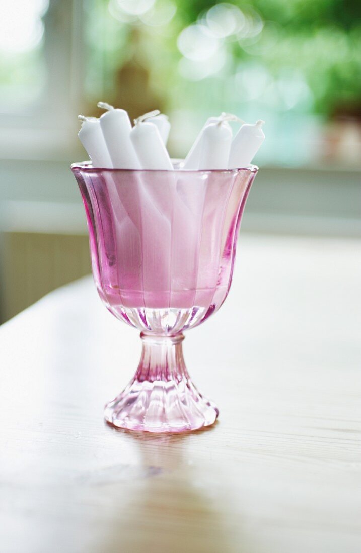 Violettes Stielglas mit weissen Kerzen
