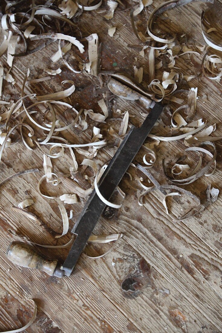 Holzspäne und ein traditionelles Schälmesser auf altem Dielenfussboden in Schreinerwerkstatt