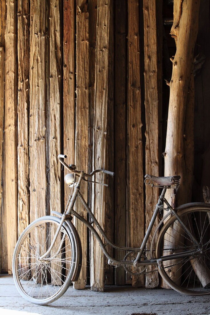 Vintage bicycle in front of stock of wooden beams in barn of rough-wood carpenter's workshop