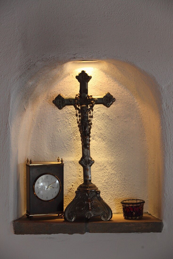 Kleine Wandnische beleuchtet, mit Devotionalie und Tischstanduhr