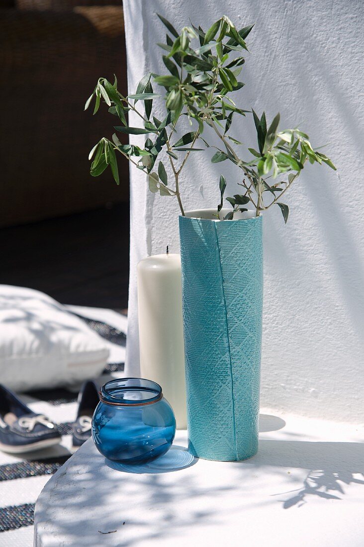 Olivenzweige in türkisfarbener Bodenvase, Windlicht aus Glas und Bodenkerze