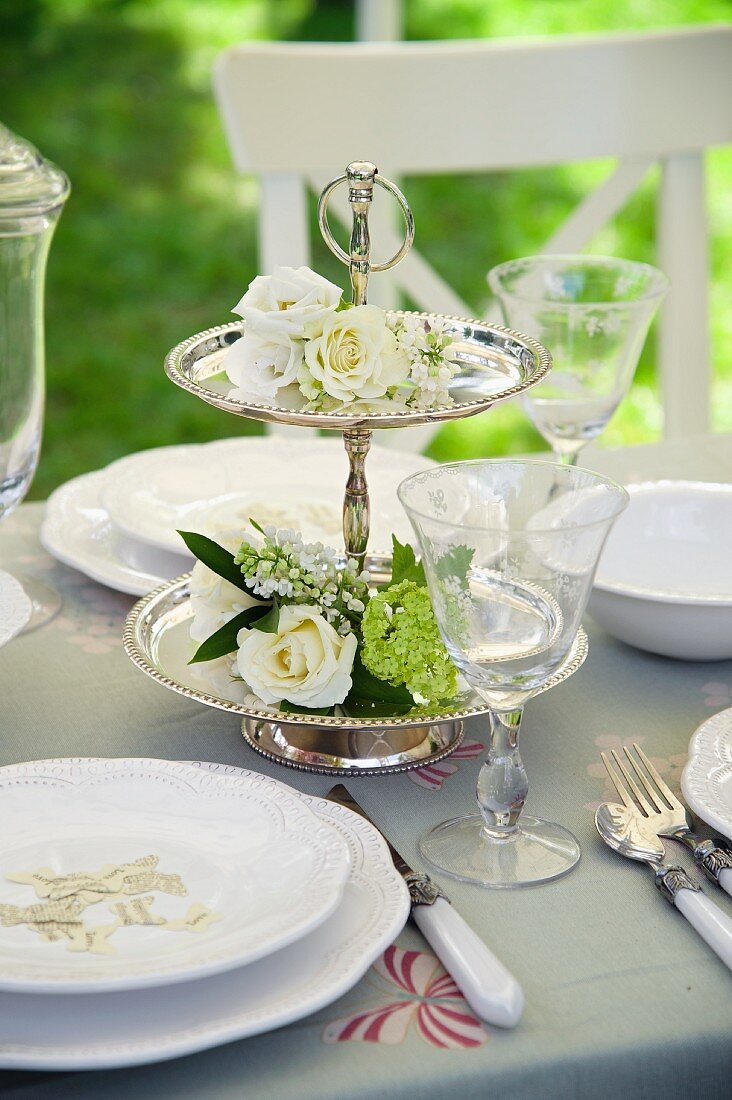 Silber Etagere mit weissen Blumen verziert auf gedeckter Hochzeitstafel
