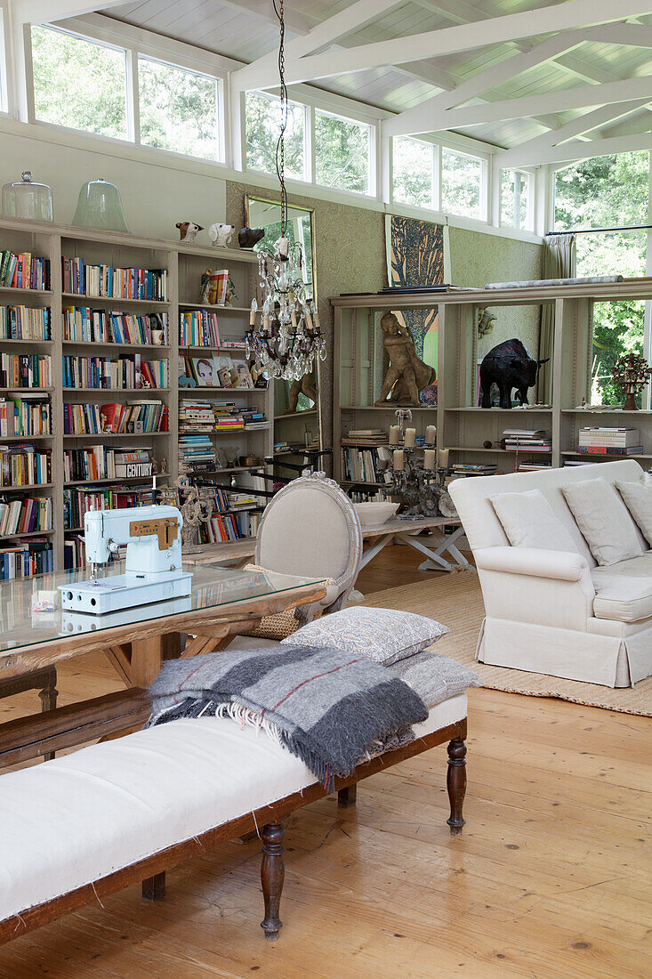 Langer Esstisch mit Polsterbank, im Hintergrund Sofa und Bücherregal im Wohnraum