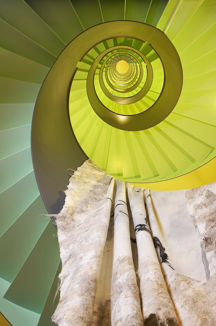 Deceptive view up lime green spiral stairwell with cloth hanging over balustrade