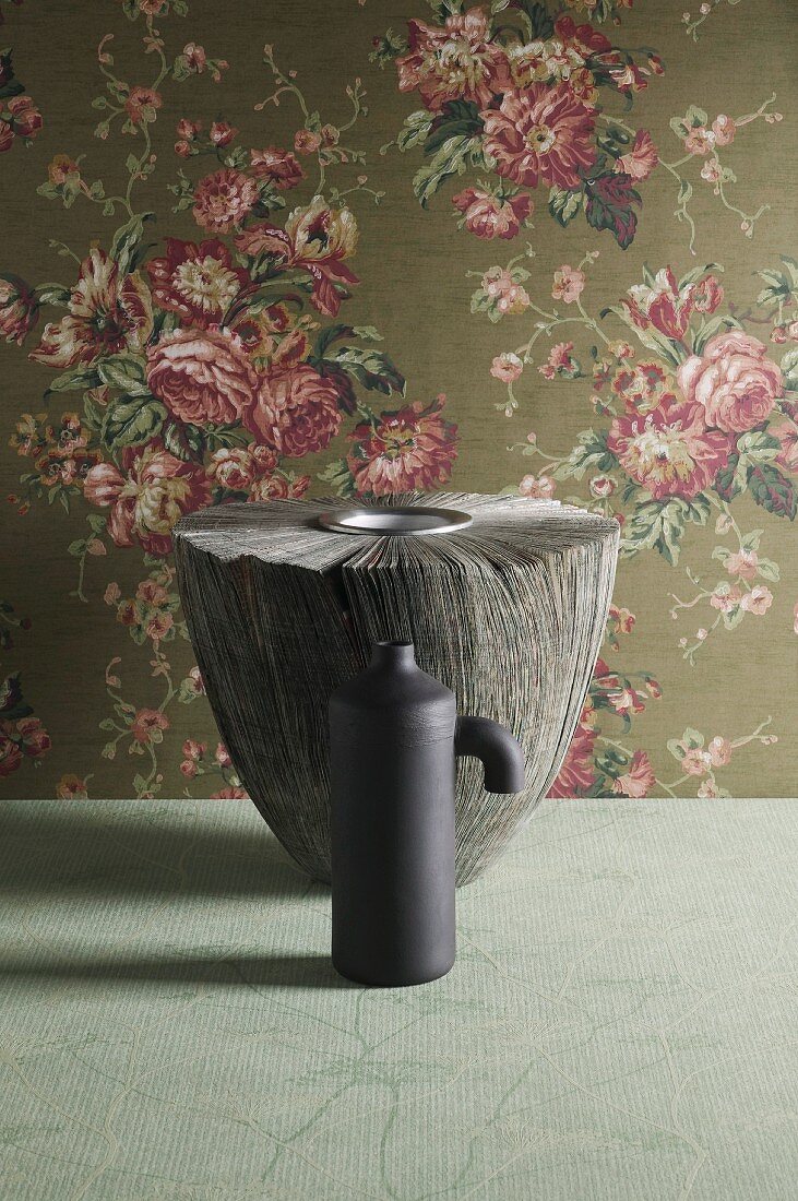 Two grey vases in front of elegant rose-patterned wallpaper