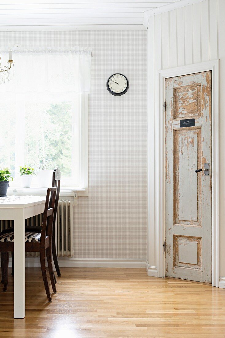 Dining set below window, glossy parquet floor and vintage interior door in wood-panelled, angled wall
