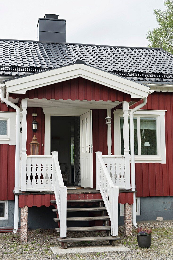 Traditionelles Schwedenhaus mit Veranda, Treppenabgang und geöffneter Eingangstür