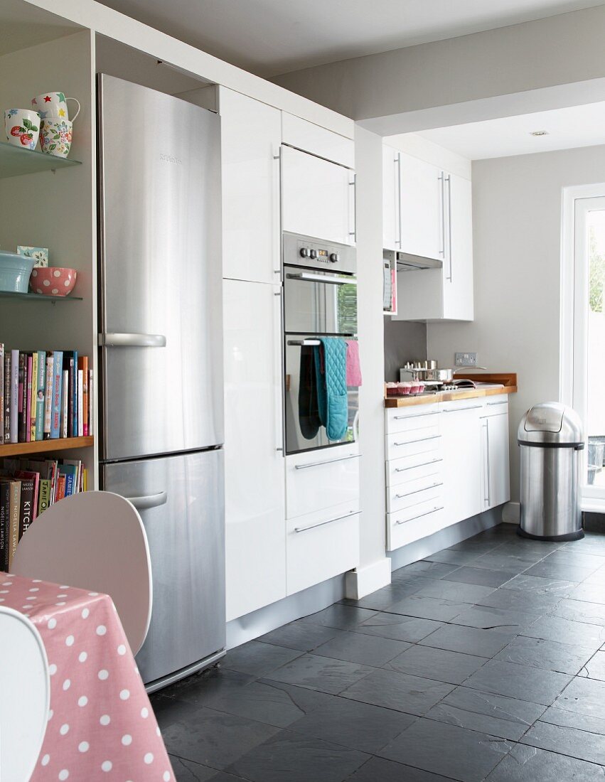 Contemporary kitchen with white fitted cupboards and integrated stainless steel fridge