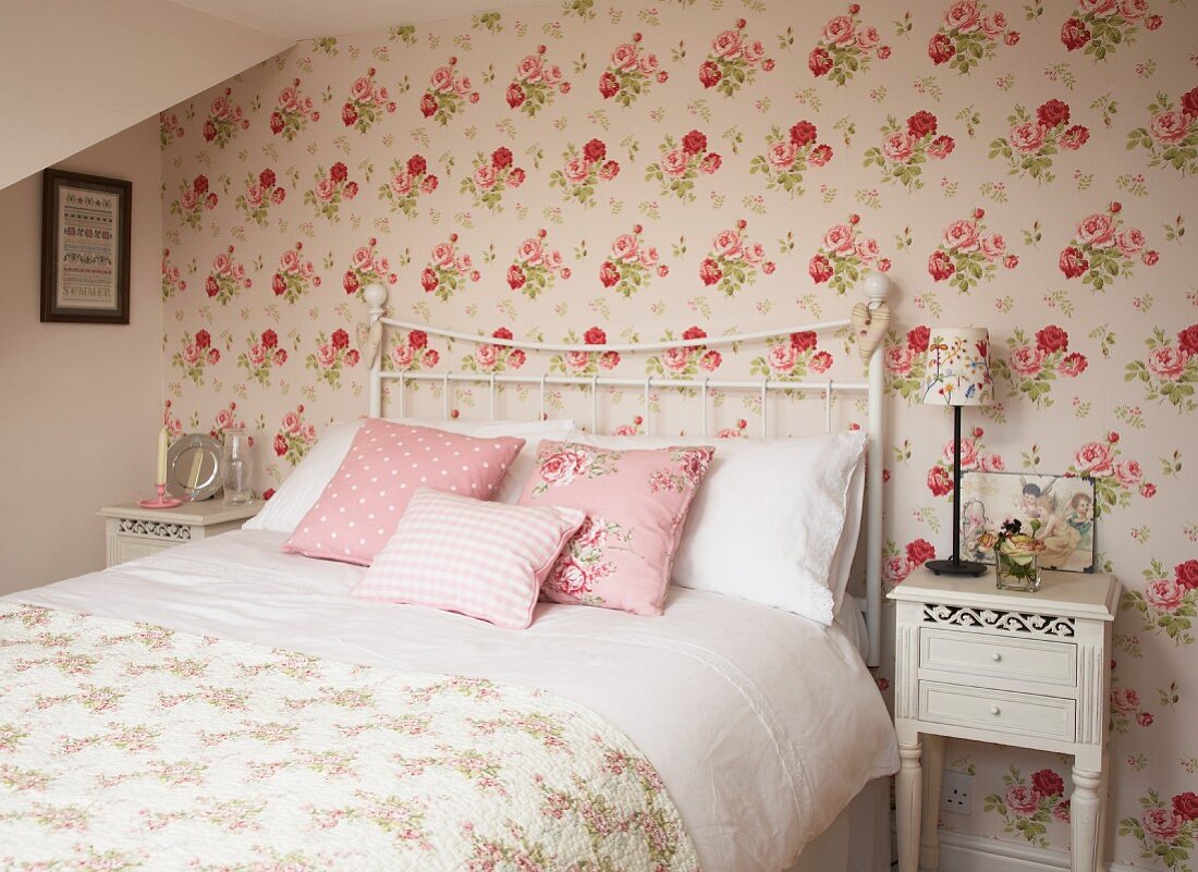 Doppelbett mit weißem Metallgittergestell in romantischem Schlafzimmer mit Blumentapete