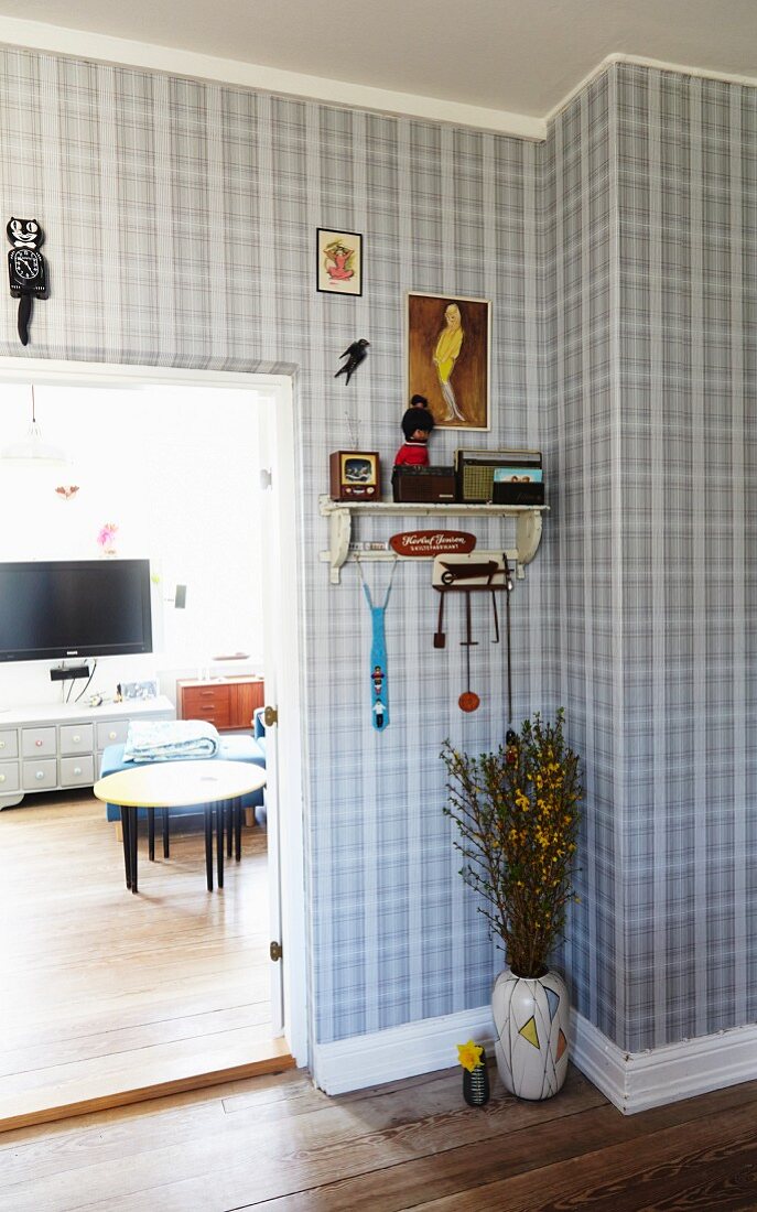 Diele mit karierter Tapete, Bodenvase unter Wandboard, neben offener Tür zu Wohnzimmer