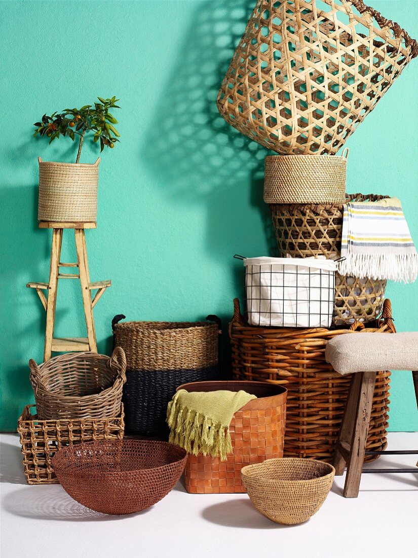 Plant pots and baskets in various woven materials against turquoise wall