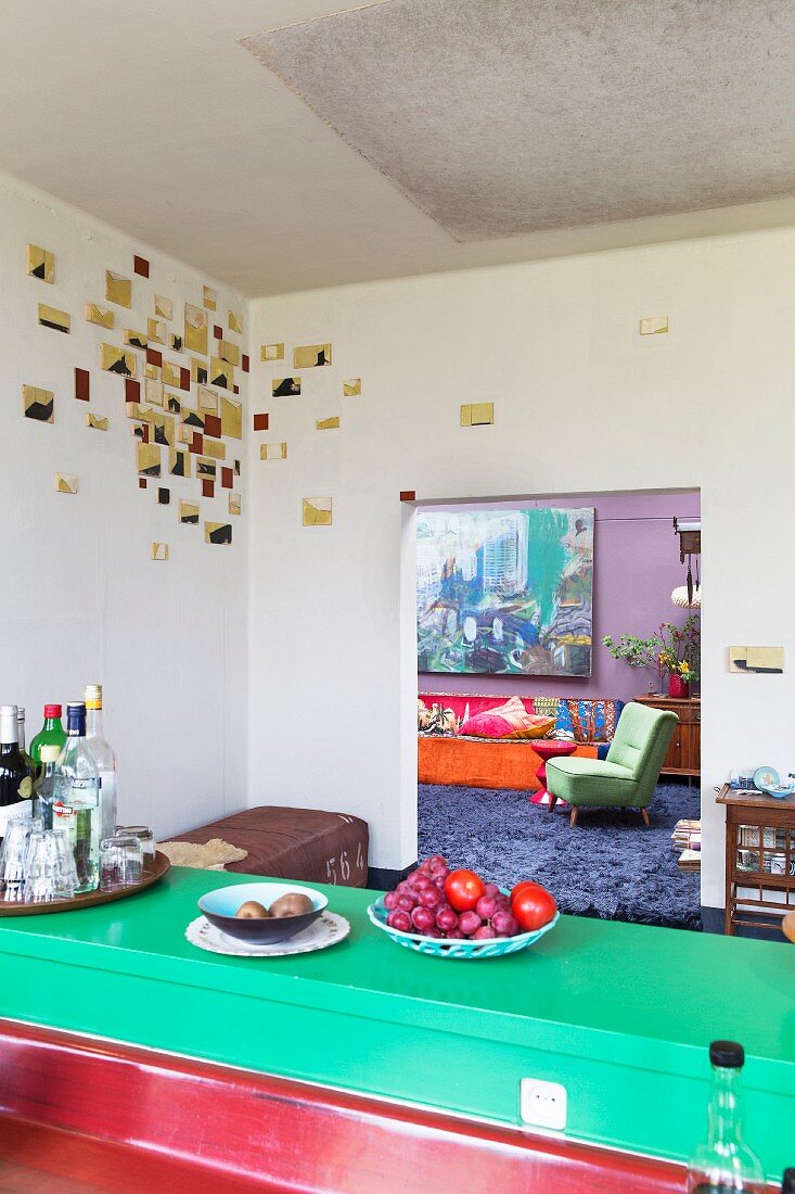 Blick von einer Loft-Küche mit künstlerischer Wanddekoration ins Wohnzimmer
