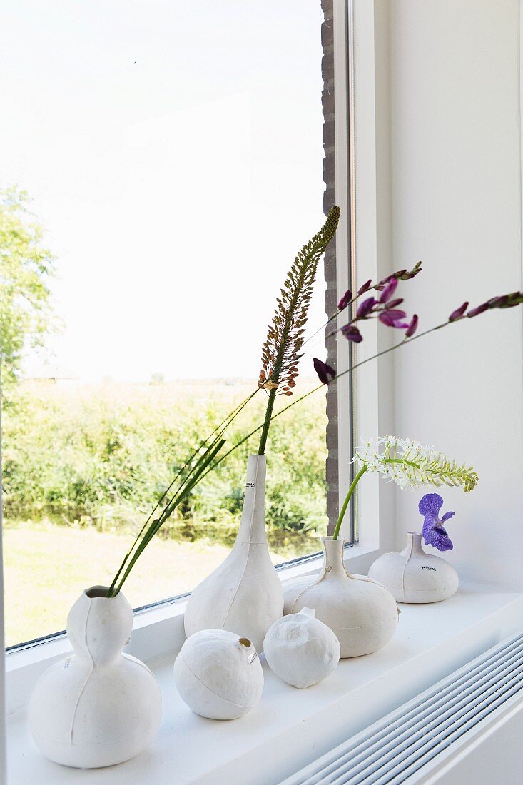 Hand-crafted, white vases shaped like gourds on windowsill
