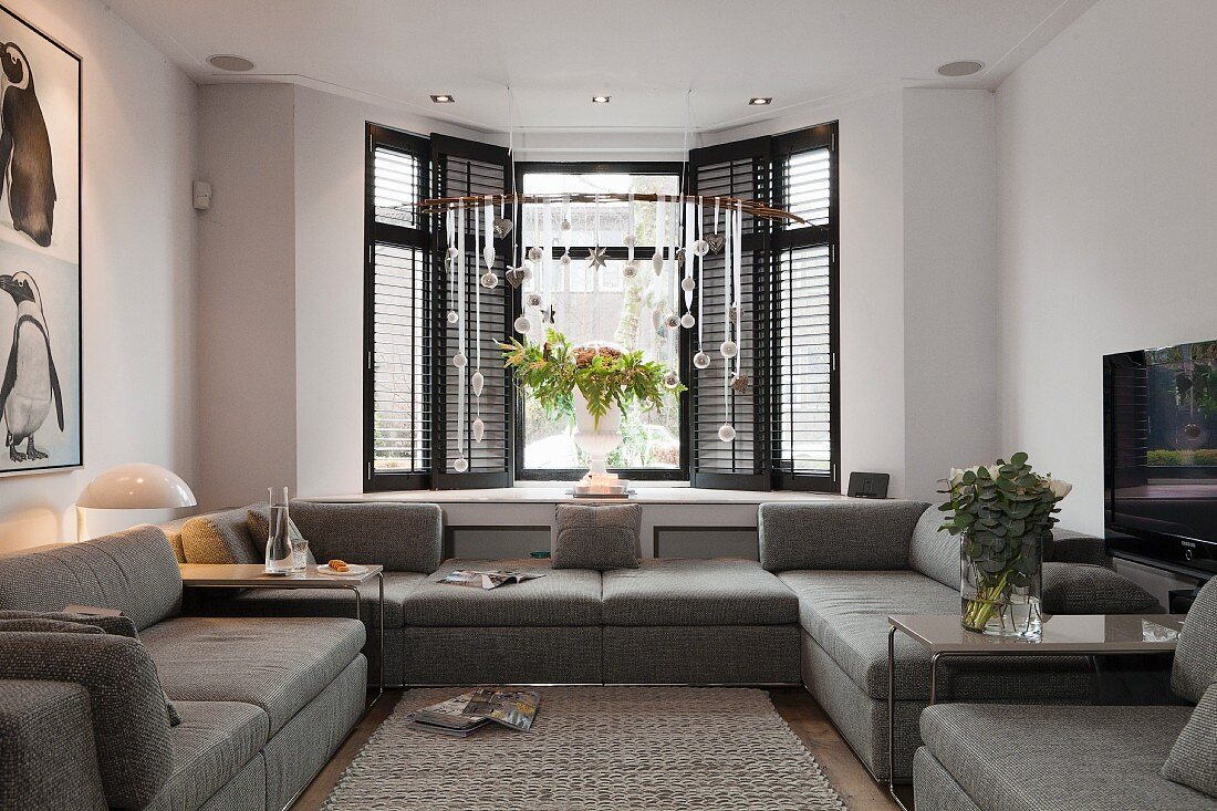 Grey, modern sofa combination in front of bay window and Christmas arrangement suspended from ceiling