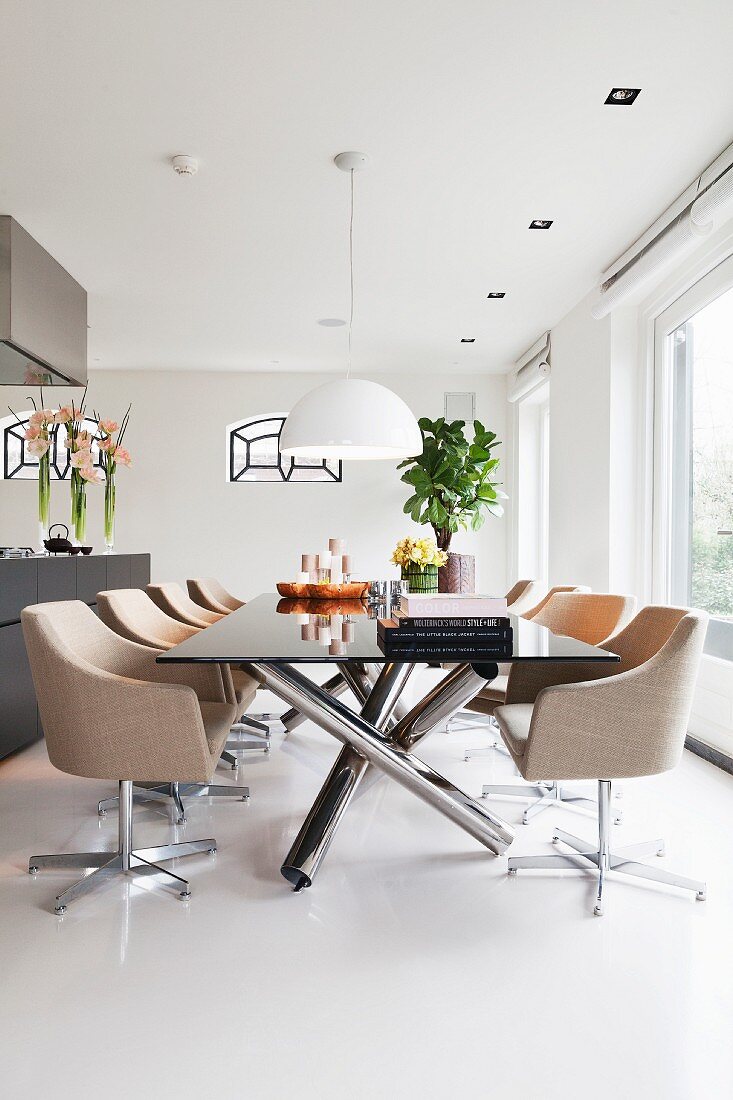 Elegant swivel chairs with pale upholstery around modern table with stainless steel frame