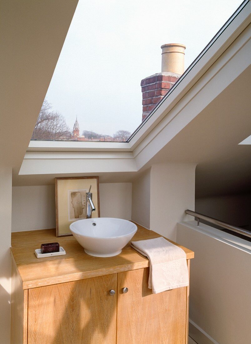 Modern washstand with base cabinet and countertop sink under skylight with a view