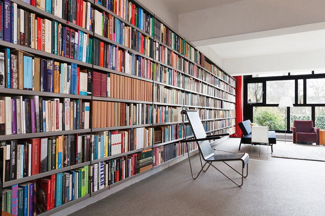 Stuhl auf Metallgestell vor Bücherwand in offenem Wohnraum mit Bauhausflair