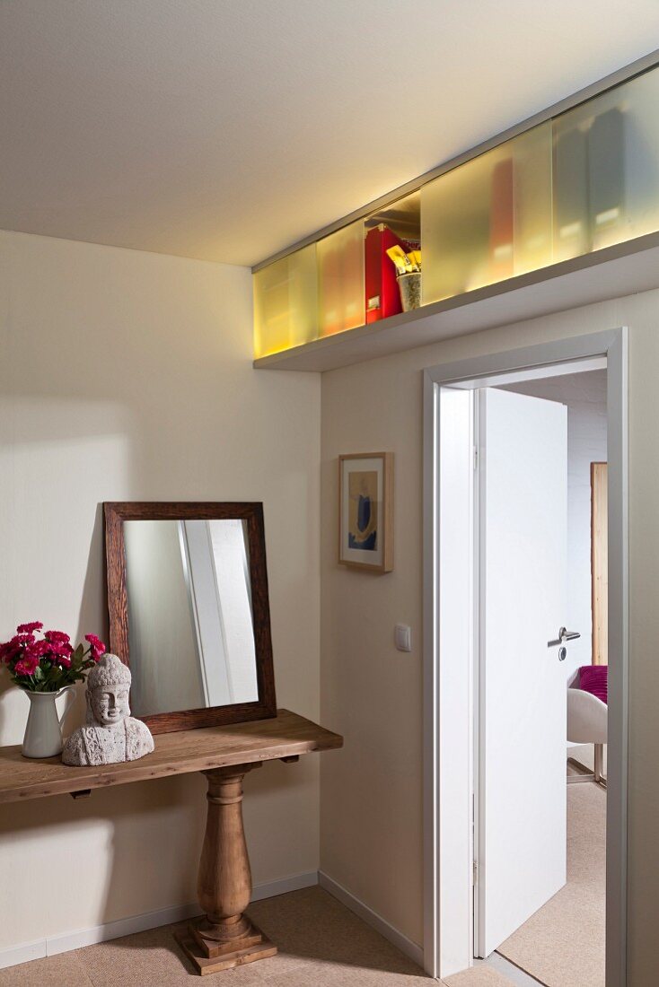 DIY storage cabinet above door with illuminated shelving behind sliding doors