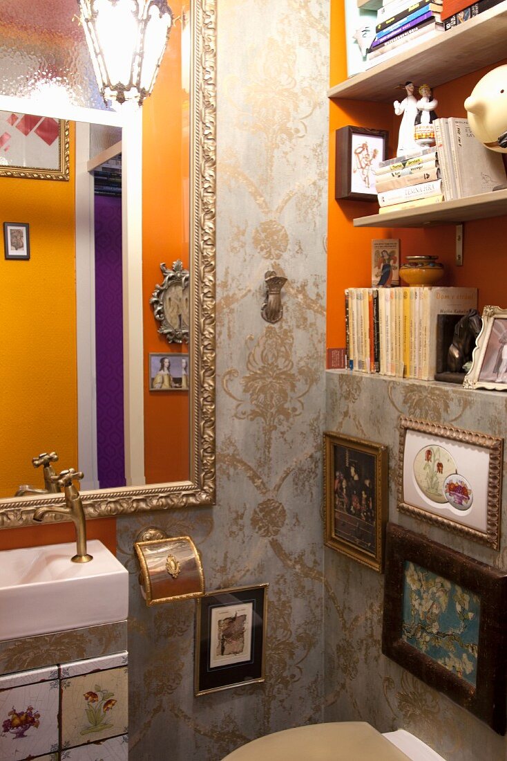Opulent dekoriertes Gäste-WC mit Ornament-Tapete, barockem Spiegel und Bildergalerie