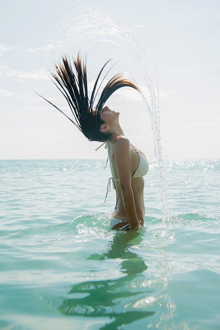 Junge Frau die Haare ins Wasser peitschend