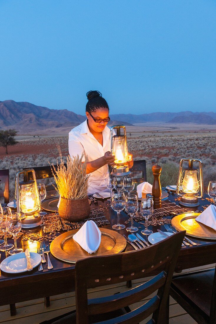 'Dune Camp' in Wolwedans, NamibRand Nature Reserve, Namibia, Africa – Sharon laying a table for a candlelight dinner