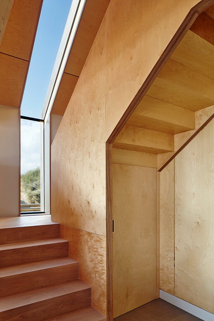 Treppenaufgang aus Holz, Podest vor schmalem, vertikalem Fensterband in zeitgenössischem Haus