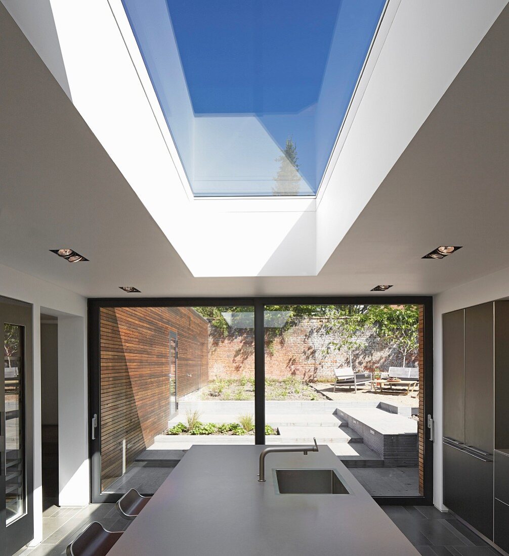 Point 7, Winchester, United Kingdom. Architect: Dan Brill Architects, 2014. View from kitchen to sunny terrace on multiple levels through sliding terrace doors