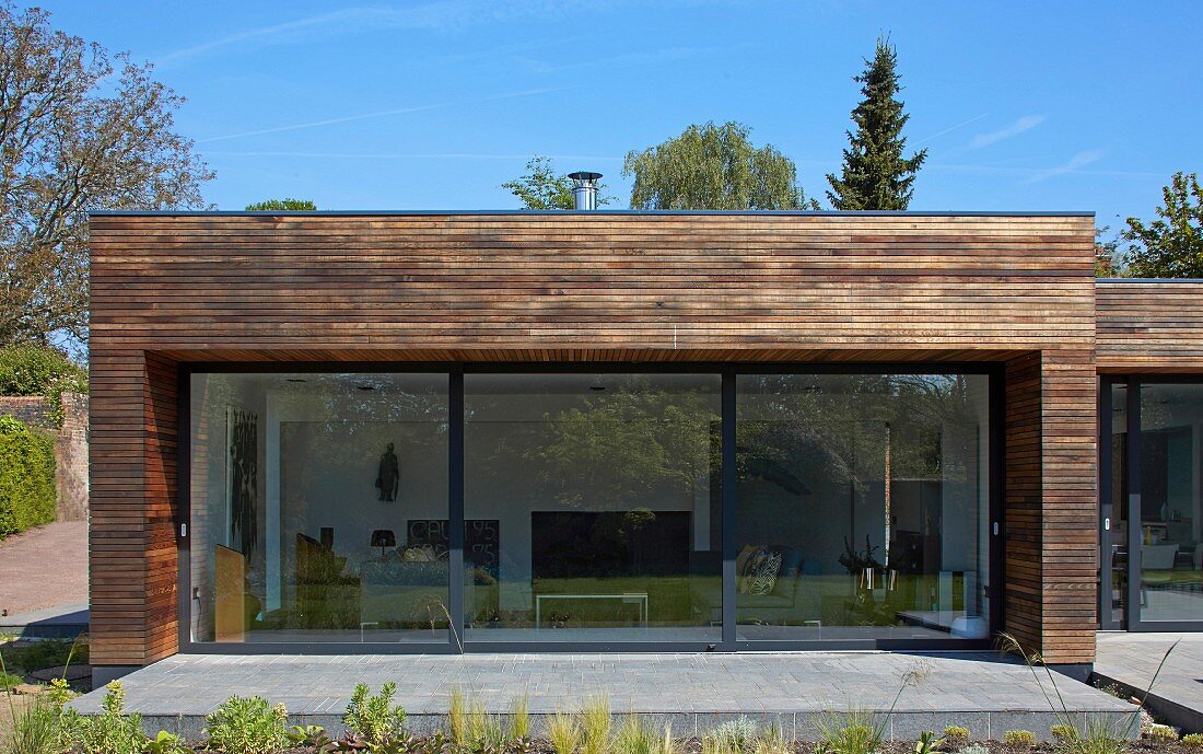 Blick von Garten auf zeitgenössisches Wohnhaus mit Terrasse und grossformatigen Glas Schiebetüren