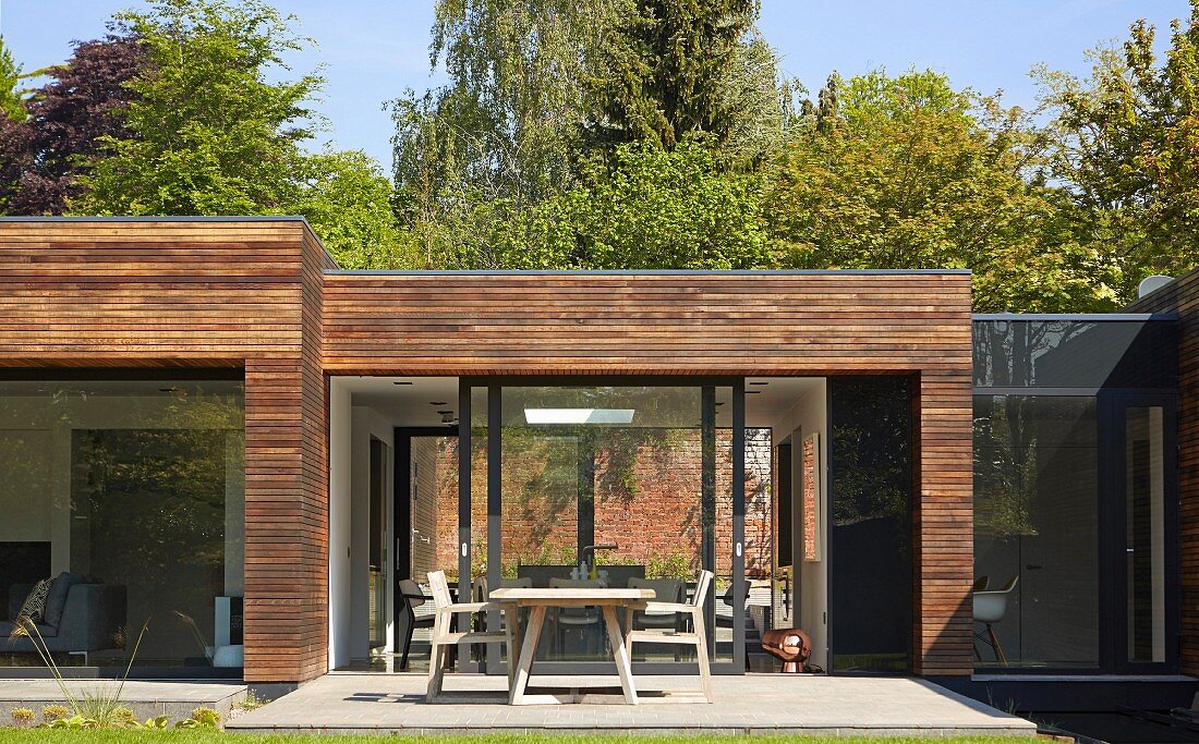 Möblierte Terrasse vor zeitgenössischem Wohnhaus mit horizontaler Holzverschalung