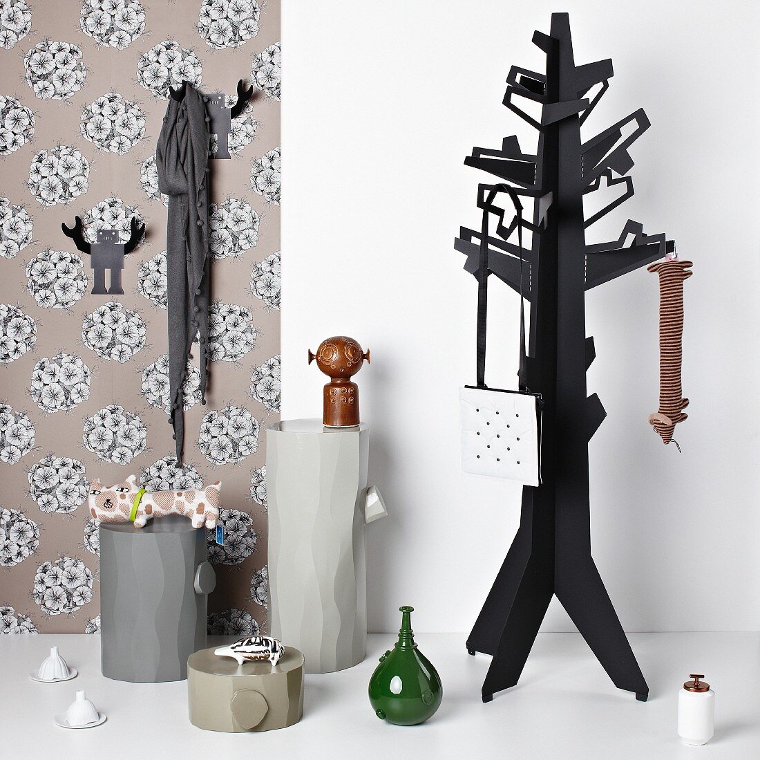 Coat stand and objets d'art on plinths against strip of floral wallpaper