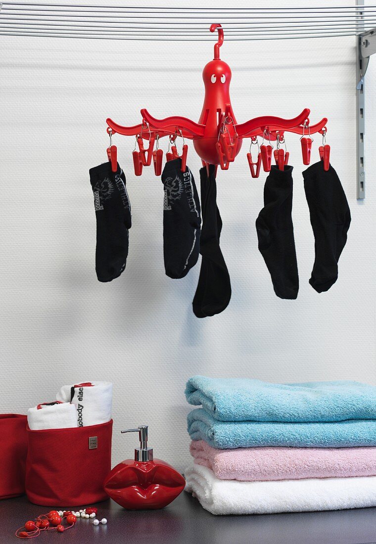 Gestapelte Handtücher unter roter, aufgehängter Wäschespinne mit Socken