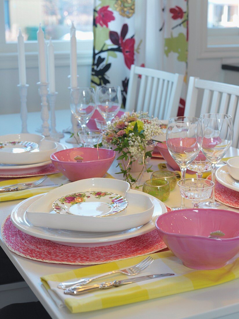 Place settings with heart-shaped plates and pink bowls on festive table