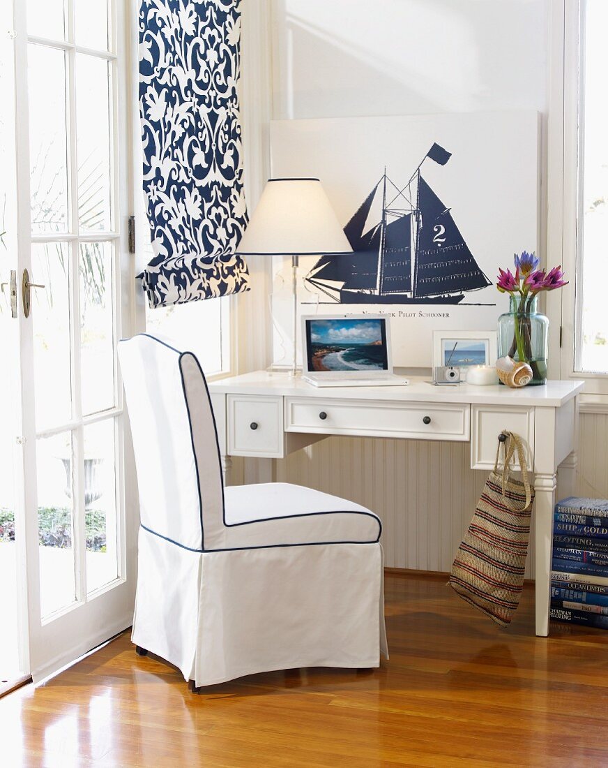 Small white desk in corner of white bedroom with nautical theme