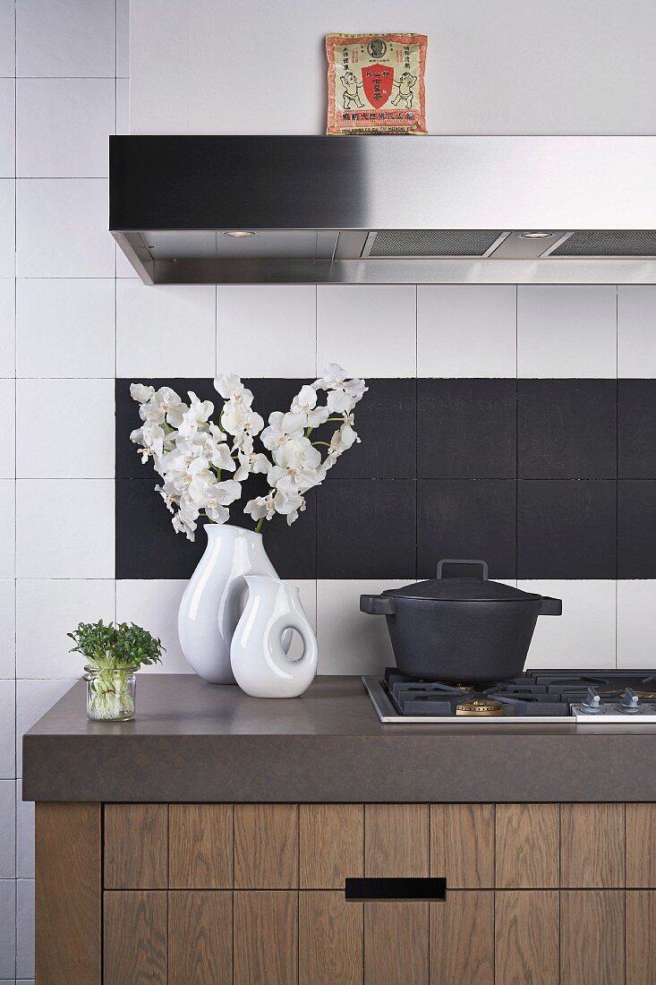 China vases and cast iron pan on kitchen counter in front of white and black wall tiles