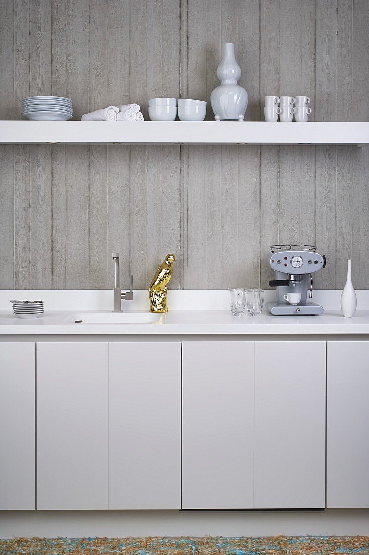 Küchenzeile und Wandbord vor Sichtbetonwand in minimalistischer, weisser Designerküche