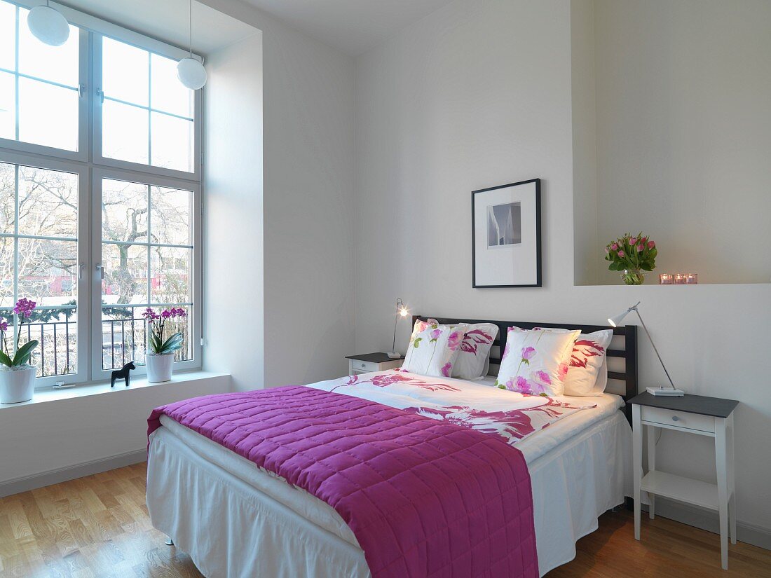 Doppelbett mit violetter Tagesdecke in weißem Schlafzimmer
